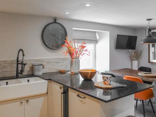een keuken met een wastafel en een klok aan de muur bij Mill House - Uk50646 in Stithians