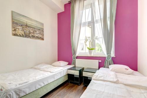 two beds in a room with purple walls at 3 City Hostel in Gdańsk