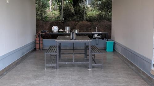 a kitchen with a sink and a table and chairs at Meghamalhar in Mānantoddy