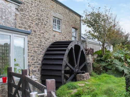 een grote molen die buiten een bakstenen gebouw staat bij The Cottage - Uk50652 in Stithians