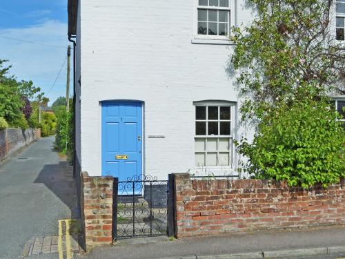 a blue door on a white house with a brick fence at Owl Cottage in Fordwich