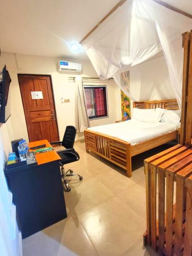 a bedroom with a bed and a desk with a desk at Sand and Sunset in Kendwa