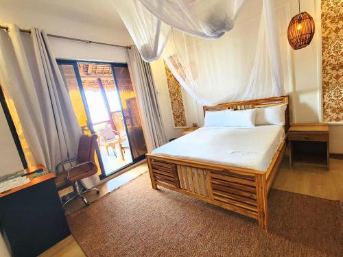a bedroom with a large bed and a window at Sand and Sunset in Kendwa