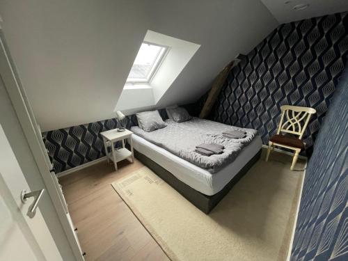 a small attic bedroom with a bed and a chair at Guest apartment on horse farm in Höganäs