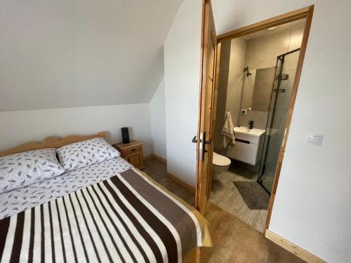 a bedroom with a bed and a bathroom with a shower at Domki przy szlaku Szczebel in Lubień