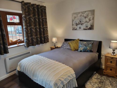 a bedroom with a bed and two windows with curtains at Cozy Studio Newly Furnished in Colchester