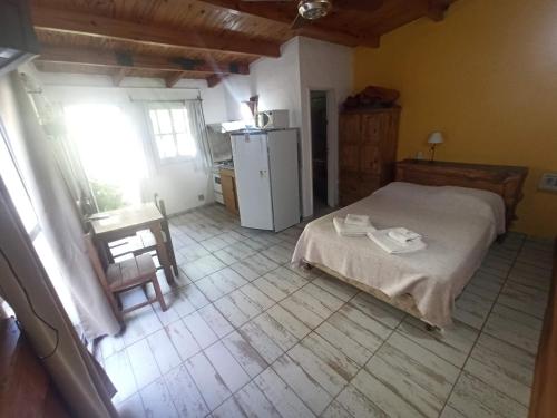 a bedroom with a bed and a table and a refrigerator at Complejo EL ALTO in Tanti