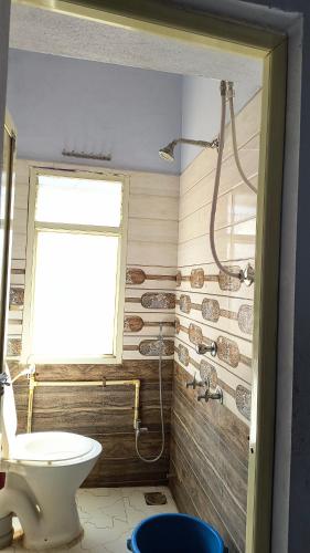 a bathroom with a toilet and a window at Modern Guest House in Ujjain