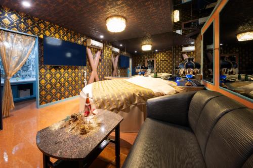 a room with a bed and a couch and a table at ホテル ダブルイン茨木 in Ibaraki