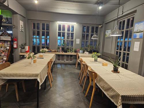 uma sala de jantar com mesas, cadeiras e janelas em Mandalar Arch 39 Hotel em Chiang Mai