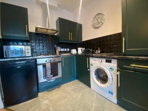 a kitchen with green cabinets and a washing machine at City Apartment - Sleeps 4 & Free Parking in Belfast
