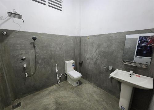 ein Badezimmer mit Dusche, Toilette und Waschbecken in der Unterkunft Cinnamon Grove in Udawalawe