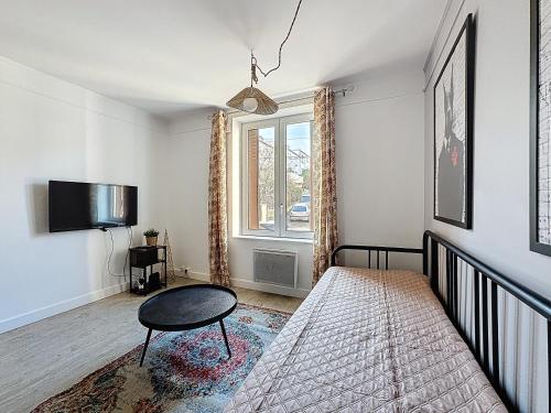 une chambre avec un lit, une table et une fenêtre dans l'établissement Rue Bien Assis avec jardin terrasse, à Clermont-Ferrand