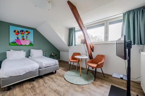 een slaapkamer met een bed, een tafel en stoelen bij BergOpwaerts in Sint Odiliënberg