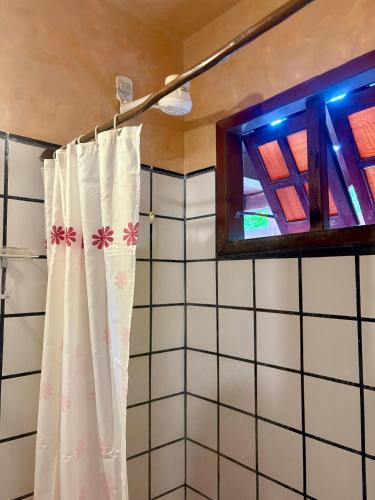 a bathroom with a shower curtain and a window at Novos Baianos Hostel e Pousada in Arraial d'Ajuda