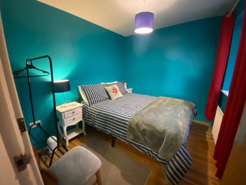 a bedroom with a bed with a blue wall at City Apartment - Sleeps 4 & Free Parking in Belfast