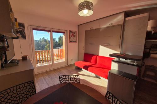 ein Wohnzimmer mit einem roten Sofa und einem Balkon in der Unterkunft Cozy apartment "WAPITI" at the foot of the slopes in Les Déserts