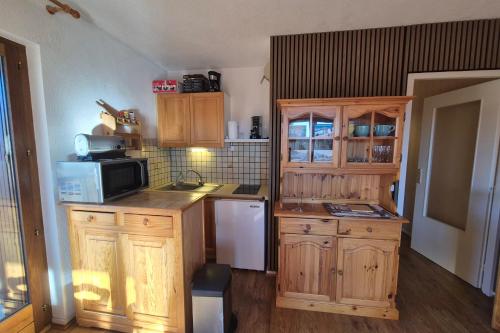 eine Küche mit Holzschränken und einer Mikrowelle in der Unterkunft Appartement 4 personnes au pied des pistes in Les Déserts