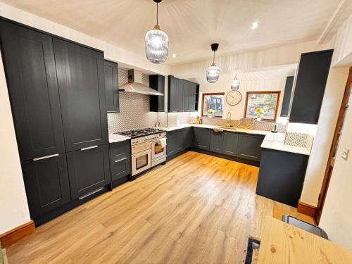 a kitchen with black cabinets and a wooden floor at "Ivyholme" Superb Premium House in Central Durham Location in Durham