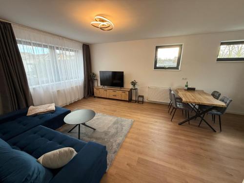 un salon avec un canapé bleu et une table dans l'établissement Modernes Apartment mit Parkplatz und 24h Check-in, à Niederdorla