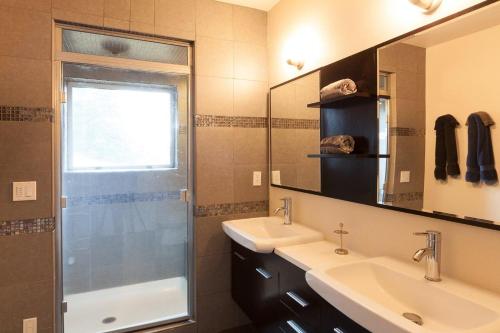 ein Bad mit 2 Waschbecken, einer Dusche und einem Spiegel in der Unterkunft Mountain House in Mount Hood