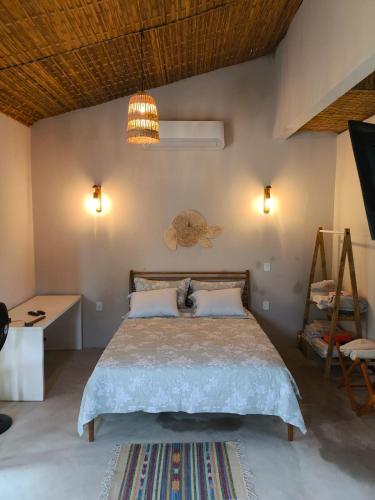 a bedroom with a bed and a table and lights at Há Mar Chalés Corumbau in Corumbau