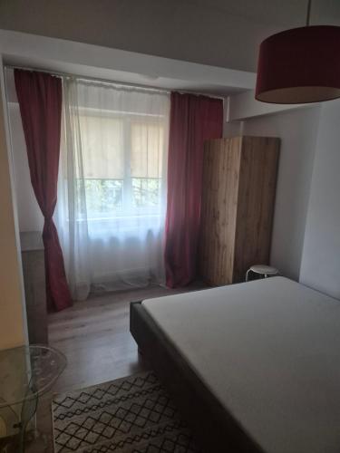 a bedroom with a bed and a window with pink curtains at Apartament central in Craiova