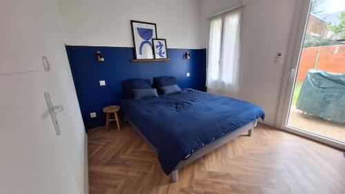 Un dormitorio con una cama azul y una ventana. en La Maison Des Pins, en Le Mans