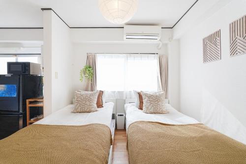 two beds in a small room with a window at Tomo House Yoyogi 302 - from 4 minutes station 代々木 302 駅から徒歩4分 in Tokyo
