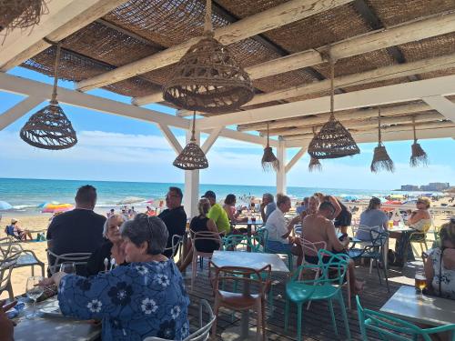 Un grupo de personas sentadas en mesas en la playa. en Het Verwende Nest, en La Mata