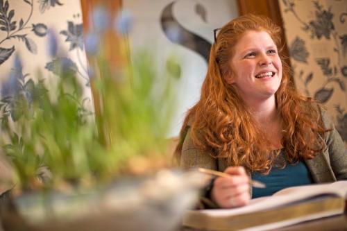 a woman with red hair writing in a book at Saplinbrae Hotel and Lodges in Mintlaw