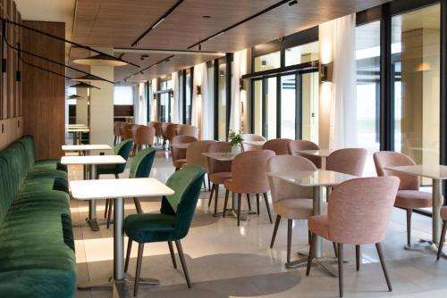 a dining room with tables and green chairs at Hôtel des Innovations in Marly