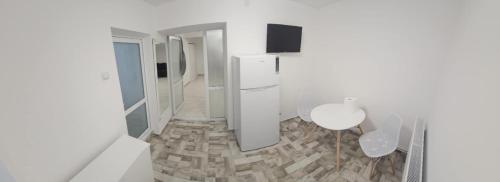 a white room with a table and a refrigerator at Garsoniera in Craiova