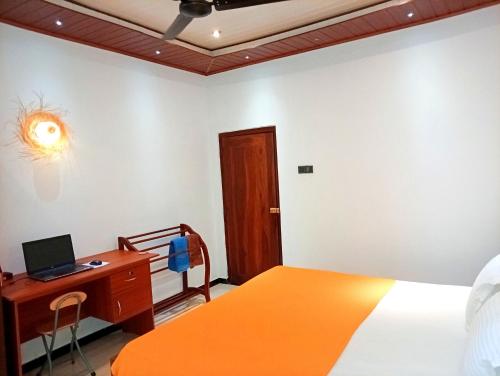 une chambre avec un lit, un bureau et un ordinateur dans l'établissement Happy Three Holiday Homes, à Hikkaduwa
