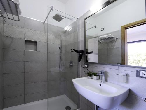 a bathroom with a sink and a shower with a mirror at Oasis Hotel Residence Resort in Lampedusa