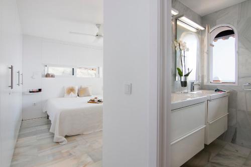 a white bedroom with a bed and a sink at Duplex Penthouse with Swimming Pool in La Herradura