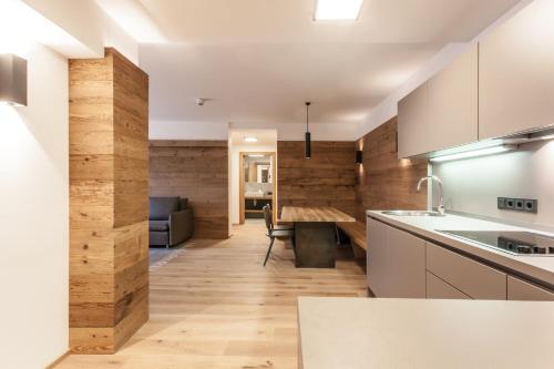 a kitchen with white cabinets and a wooden wall at Hubertus Logis Apartments in Brixen im Thale