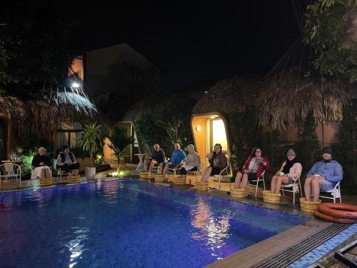 un gruppo di persone sedute intorno a una piscina di notte di Tam Coc Sky Bungalow a Ninh Binh