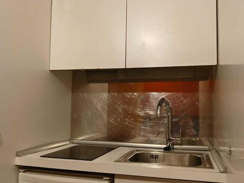 - une cuisine avec un évier et des placards blancs dans l'établissement Studio cosy à Tignes, au pied des pistes et commerces - FR-1-411-481, à Tignes