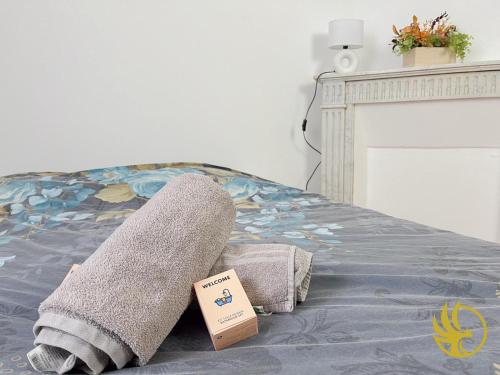 a pair of towels and a book on a bed at Le Spacieux, Gare et Centre, Idéal Pro in Saint-Quentin