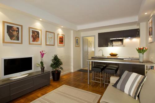 Il comprend un salon avec une télévision et une cuisine. dans l'établissement Le California, à Juan-les-Pins