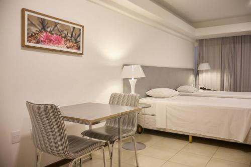 a hotel room with a bed and a table and chairs at Celita Franca - WS Urban in Feira de Santana