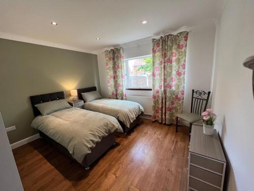 a bedroom with two beds and a window at Spacious modern three Bedroom Bungalow ample parking