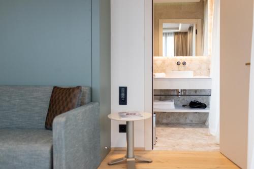 a living room with a couch and a mirror at Hôtel des Innovations in Marly