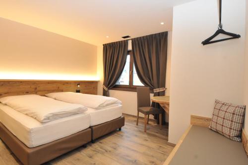 a bedroom with a bed and a desk and a window at Borch Chalet - Exclusive Apartments in Livigno