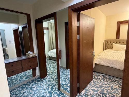 ein Zimmer mit einem Schlafzimmer mit einem Bett und einem Spiegel in der Unterkunft Luxury 2BR apartment near Muscat Mall in Ma‘ābīlah