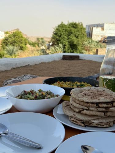 una mesa con platos de comida y tazones de comida en Per Ankh - Heissa island - Aswan, en Asuán