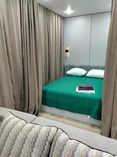 una camera da letto con letto con lenzuola e tende verdi di Сейфулина 31 a Balqash