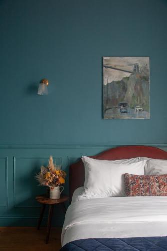 a blue bedroom with a bed and a painting on the wall at Lido Townhouse in Bristol