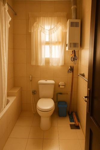 a small bathroom with a toilet and a window at Cairo Airport Oasis Cozy Convenient in Obour